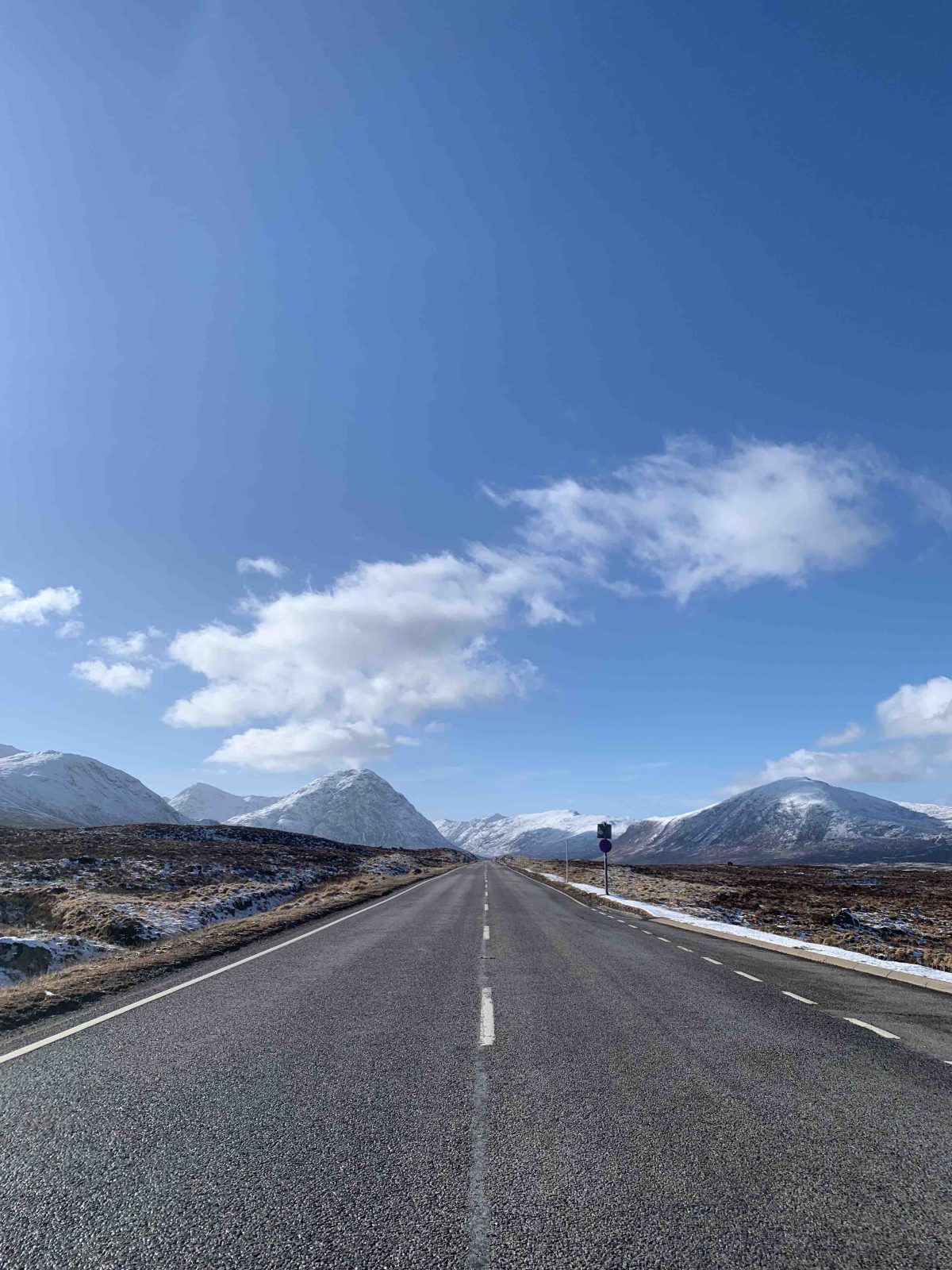 an image of a tarmac road between snow-covered mountains in Glencoe